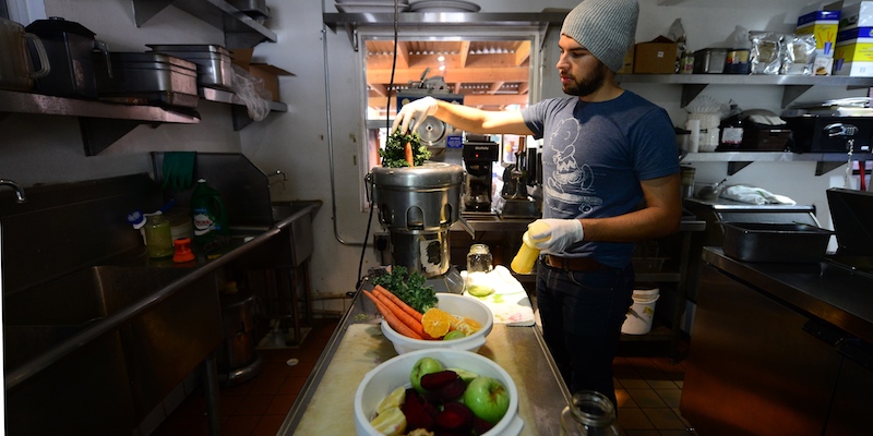 Un lavoratore del Juice Bar di Silver Lake, in California, mette carote e cavolo riccio in una macchina per fare succhi, il 17 settembre 2013 (FREDERIC J. BROWN/AFP/Getty Images)