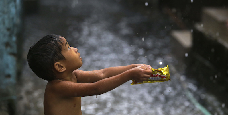 Un bambino raccoglie gocce d'acqua nel paesino allagato di Navotas, nelle Filippine, 17 luglio 2018
(AP Photo/Aaron Favila)