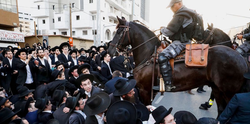 Un poliziotto israeliano in mezzo a una folla di uomini ebrei ultraortodossi (JACK GUEZ/AFP/Getty Images)
