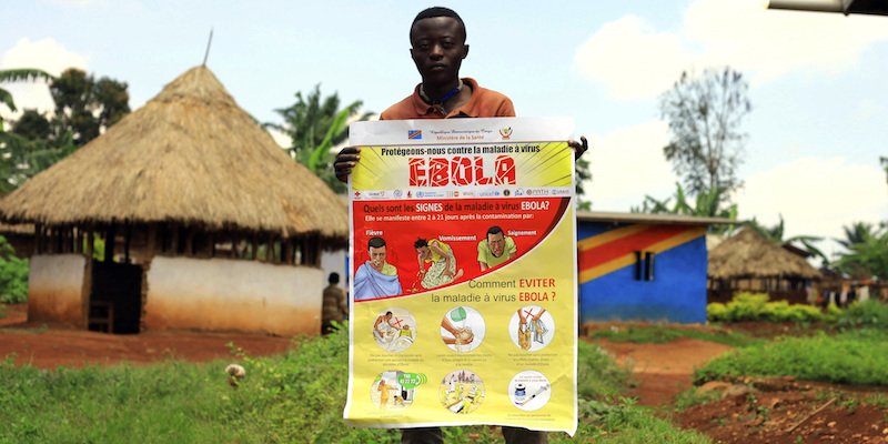 Un uomo mostra un poster informativo su ebola a Mangina, nel nord-est della Repubblica Democratica del Congo, l'8 agosto 2018 (AP Photo/Al-hadji Kudra Maliro)
