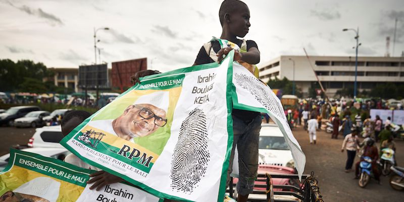 Un bambino con un cartellone elettorale della campagna dell'attuale presidente del Mali e candidato alle elezioni presidenziali Ibrahim Boubacar Keita, a Bamako, il 10 agosto 2018 (MICHELE CATTANI/AFP/Getty Images)