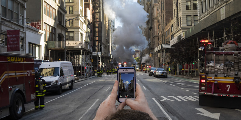 Un uomo riprende il vapore diffuso dall'esplosione di un tubo sulla Fifth Avenue di New York, il 19 luglio 2018 (Drew Angerer/Getty Images)
