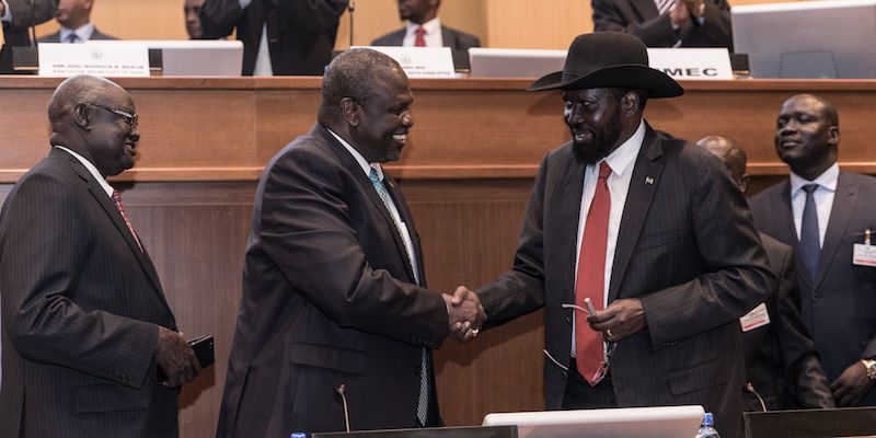 Il presidente del Sud Sudan Salva Kiir (con il cappello) e il suo ex vicepresidente poi diventato capo dei ribelli Riek Machar i stringono la mano dopo aver firmato un nuovo accordo di pace ad Addis Ababa, in Etiopia, il 12 settembre 2018 (YONAS TADESSE/AFP/Getty Images)
