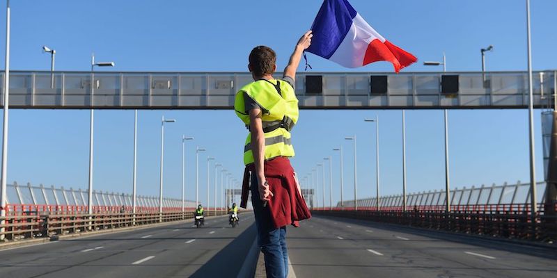 Un "gilè giallo" sventola una bandiera francese a Bordeaux, nel sud-ovest della Francia, 17 novembre 2018 (NICOLAS TUCAT/AFP/Getty Images)