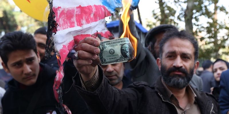 Un manifestante brucia una banconota di 1 dollaro di fronte all'ex ambasciata statunitense a Teheran, 4 novembre 2018 (ATTA KENARE/AFP/Getty Images)