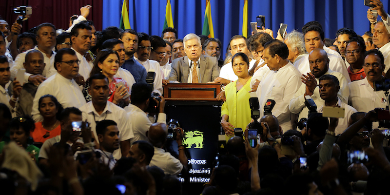 Il primo ministro dello Sri Lanka Ranil Wickeremesinghe, al centro, in mezzo ai deputati suoi sostenitori, dopo essersi reinsediato come capo del governo, a Colombo, il 16 dicembre 2018 (AP Photo/Eranga Jayawardena)