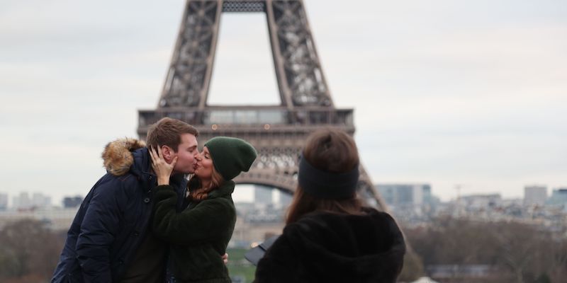Due turisti si fanno fotografare mentre si baciano con la Torre Eiffel sullo sfondo, il 31 dicembre 2018 (ZAKARIA ABDELKAFI/AFP/Getty Images)