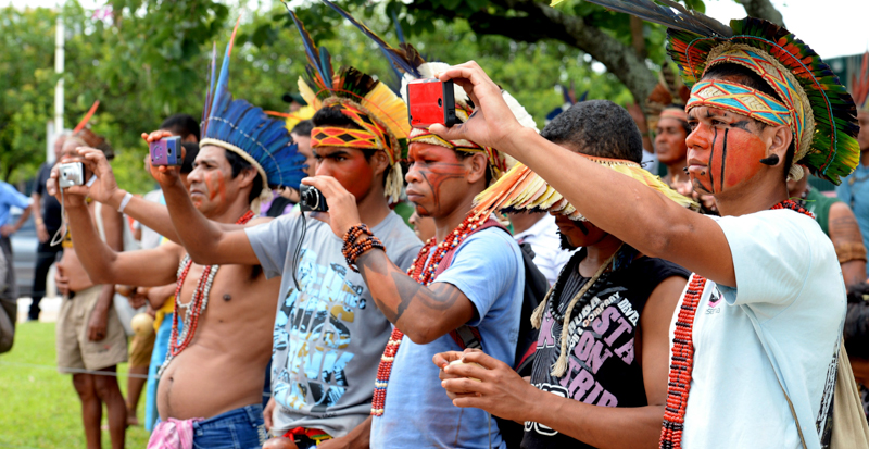Nativi brasiliani, con indosso copricapi e trucchi tradizionali, fotografano una protesta contro una legge su una nuova demarcazione dei territori indigeni in Brasile. (EVARISTO SA/AFP/Getty Images)