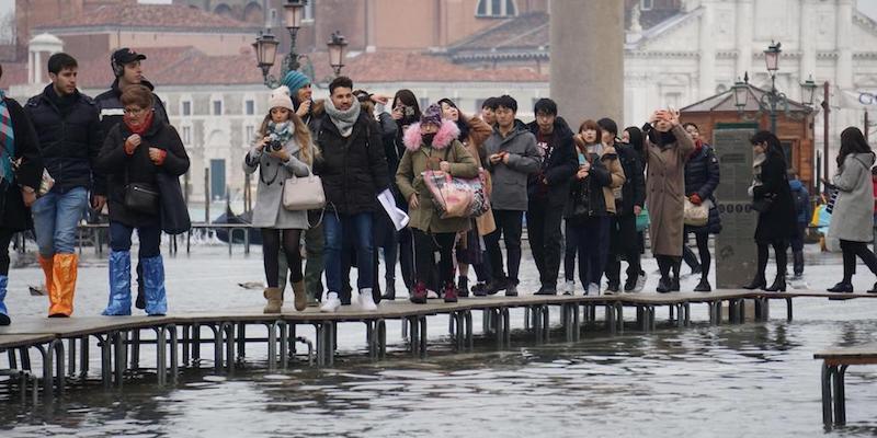 Turisti e residenti camminano sulle passerelle per l'acqua alta in piazza San Marco a Venezia, il 2 febbraio 2019 (ANSA/ANDREA MEROLA)