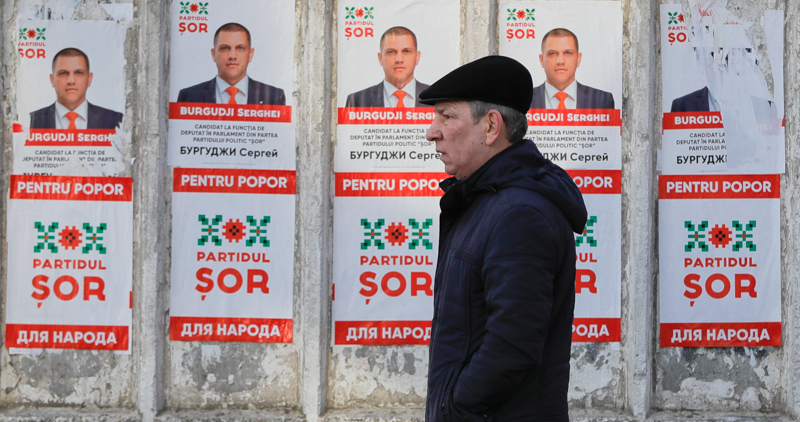 Un uomo passa davanti ad alcuni cartelli elettorali a Chisinau. (AP Photo/Vadim Ghirda)