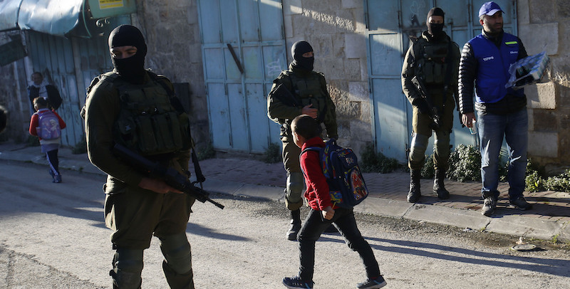 Un osservatore palestinese controlla i bambini che vanno a scuola in Cisgiordania mentre le strade sono controllate dall'esercito israeliano, 12 febbraio 2019. (AP Photo/Majdi Mohammed)