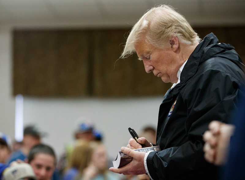 Il presidente degli Stati Uniti Donald Trump autografa una Bibbia a Smiths Station, in Alabama. (AP Photo/Carolyn Kaster)
