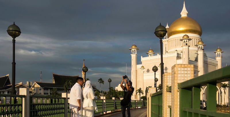 Una coppia di sposi si fa fotografare davanti alla moschea Omar Ali Saifuddien a Bandar Seri Begawan, capitale del Brunei. (AFP/LaPresse)