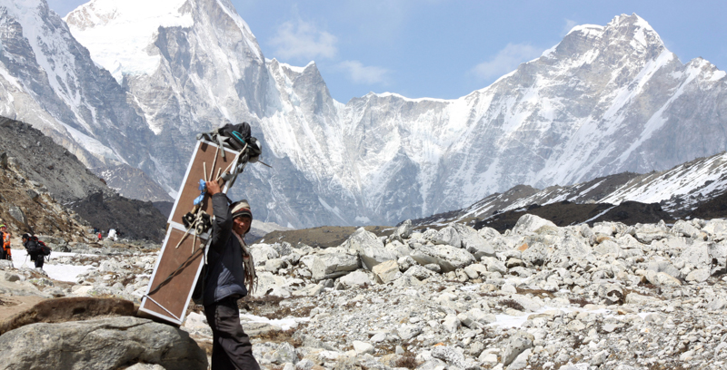 Uno sherpa porta una cassa di bombole d'ossigeno verso il campo base dell'Everest. (AP Photo/Tashi Sherpa, File)