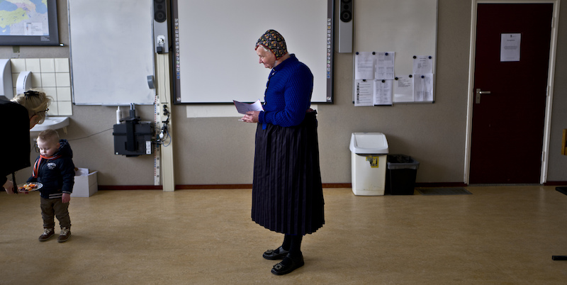 Una donna in abiti tradizionali olandesi attende il suo turno per votare in una scuola a Staphorst, nei Paesi Bassi. (AP Photo/Muhammed Muheisen)