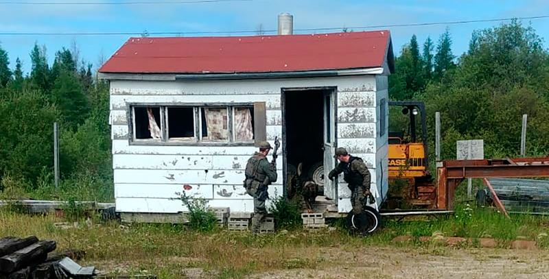 Due poliziotti perquisiscono una casa nei boschi intorno a Gillam, Manitoba. (Royal Canadian Mounted Police via AP)