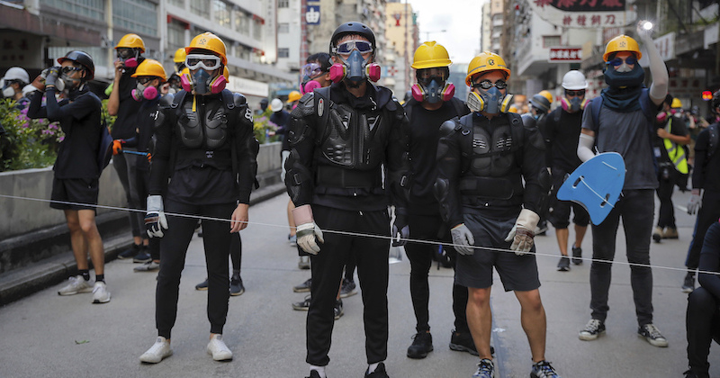 Manifestanti con protezioni sul corpo e maschere antigas per proteggersi dai proiettili di gomma e lacrimogeni lanciati dalla polizia (AP Photo/Kin Cheung)