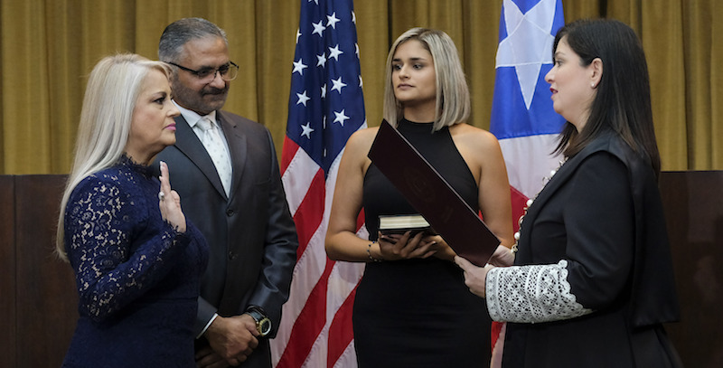 Wanda Vazquez, a sinistra, durante il giuramento come nuova governatrice di Porto Rico; con lei ci sono suo marito e sua figlia (AP Photo/Dennis M. Rivera Pichardo)