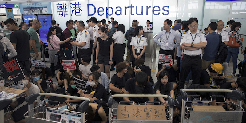 Personale dell'aeroporto di Hong Kong e manifestanti nella zona delle partenze, il 13 agosto 2019 (AP Photo/Vincent Thian)