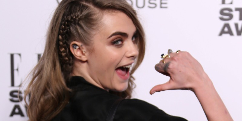 La modella Cara Delevingne indica il suo zaino sul tappeto rosso degli Elle Style Awards (Joel Ryan/Invision/AP)