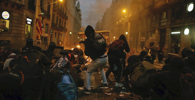 Manifestanti dietro a una barricata a Barcellona (AP Photo/Joan Mateu)