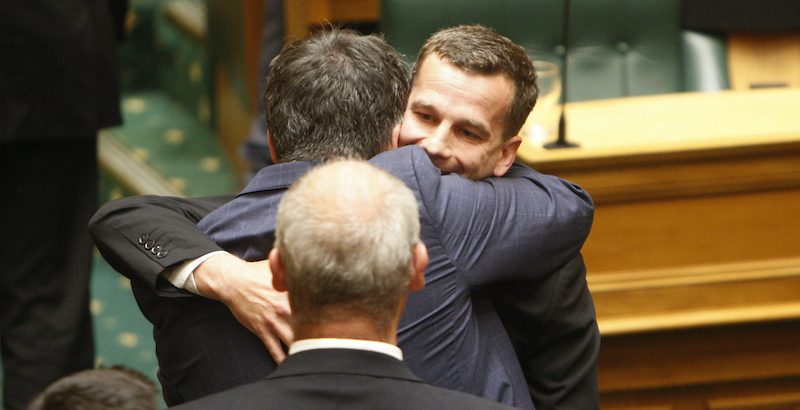 Il promotore della legge sull'eutanasia, David Seymour (al centro) abbraccia un altro parlamentare il 13 novembre a Wellington (AP Photo/Nick Perry)