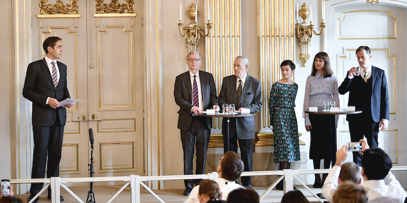 Il segretario dell'Accademia svedese Mats Malm, a sinistra, insieme a cinque membri della commissione che ha assegnato i premi Nobel per la letteratura 2018 e 2019 durante la cerimonia di annunciazione dei vincitori, il 10 ottobre 2019: da destra, Henrik Petersen, Mikael Blomqvist, Rebecka Karde, Pär Westberg e Anders Olsson (Anders Wiklund/TT via AP)