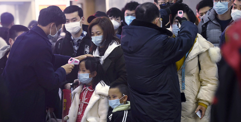Un gruppo di persone vengono controllate con termometri a infrarossi alla stazione di Hangzhou (Chinatopix via AP)