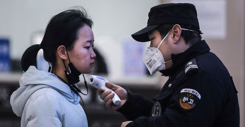 Personale di sicurezza misura la temperatura di una donna a Wuhan, in un controllo per evitare la diffusione del coronavirus (Getty Images)