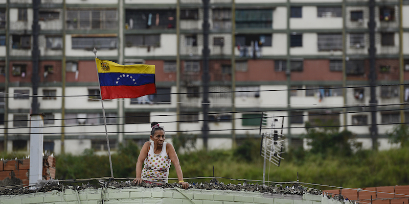 Una donna osserva i festeggiamenti per il 20esimo anniversario della firma della Costituzione venezuelana, a Caracas. (AP Photo/Matias Delacroix)