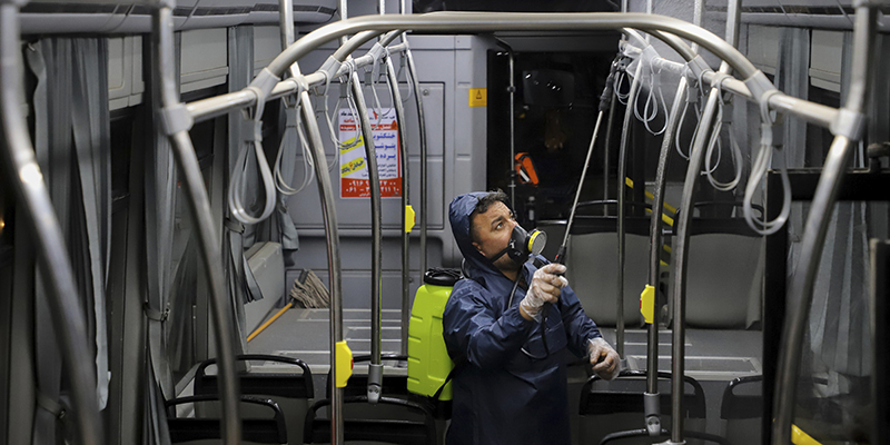 Un uomo mentre disinfetta un autobus pubblico, Ahvaz, Iran, 25 febbraio 2020 (Alireza Mohammadi/ISNA via AP)