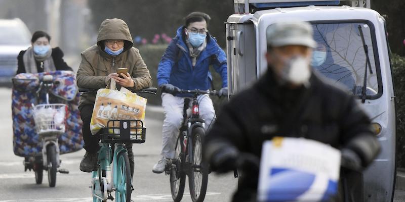 Alcune persone in bici per le strade di Pechino (Kyodo via AP Images)