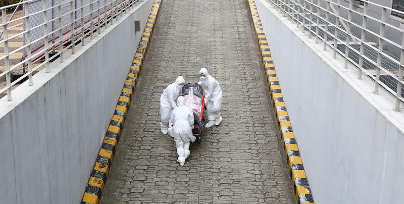 Tre operatori sanitari trasportano una barella con una persona contagiata dal coronavirus a Seul, Corea del Sud. (EPA/KIM CHUL-SOO)