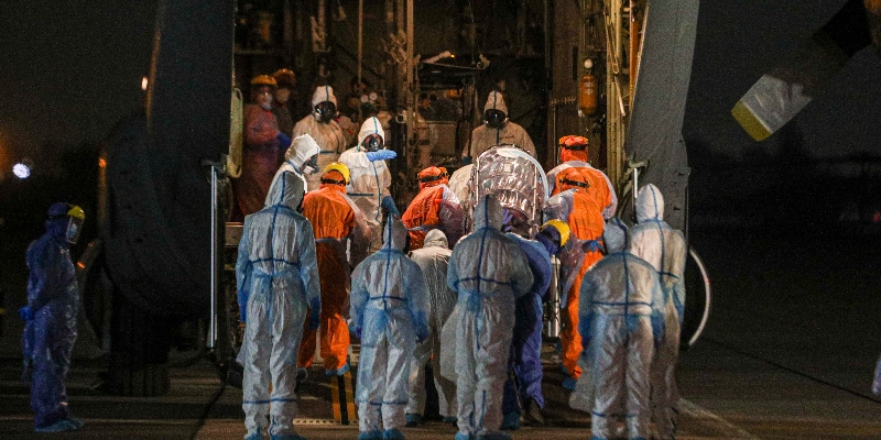 Operatori sanitari cileni spostano un paziente affetto da COVID-19 che deve essere trasportato in aereo da Santiago alla città di Concepción, per liberare spazio nelle unità di terapia intensiva degli ospedali della capitale, presso una base aeronautica a Santiago, martedì 19 maggio 2020 (AP/Esteban Felix)