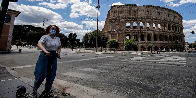 Una donna in monopattino elettrico con la mascherina protettiva a Roma davanti al Colosseo, il 27 maggio 2020 (ANSA/FABIO FRUSTACI)