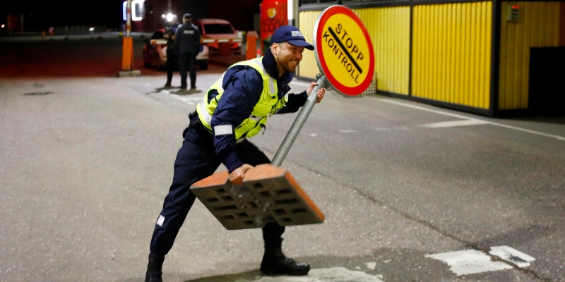 Un agente della polizia di frontiera estone rimuove un segnale di avvertimento al valico di confine di Ikla in Estonia il 15 maggio 2020 (ANSA-EPA/TOMS KALNINS)
