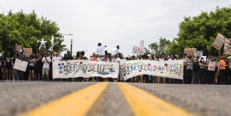 Manifestanti con un cartello che chiede di tagliare i fondi alla polizia a Minneapolis, il 6 giugno. (Stephen Maturen/Getty Images)
