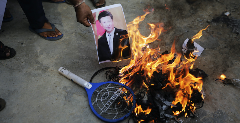 Un uomo indiano brucia una foto del presidente cinese Xi Jinping (AP Photo/Ajit Solanki)