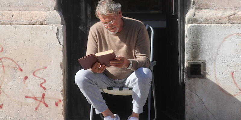 Un uomo legge un libro al sole davanti a casa a Roma, il 23 marzo 2020 (Marco Di Lauro/Getty Images)