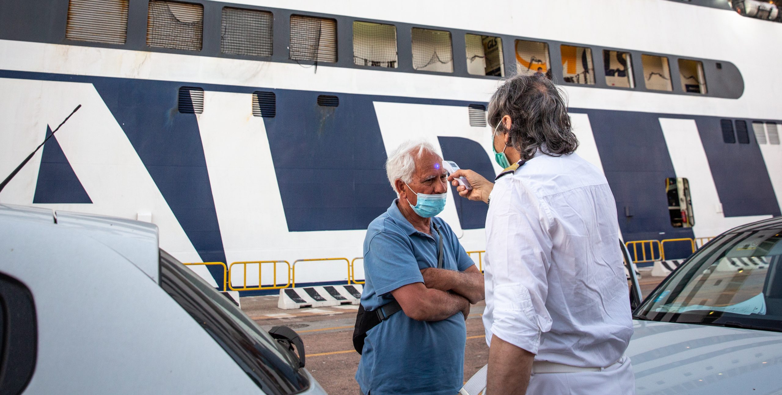 Un membro dell'equipaggio di un traghetto della Grimaldi Lines misura la temperatura a un passeggero prima dell'imbarco. Olbia, 8 luglio 2020 (Max Cavallari/Getty Images)