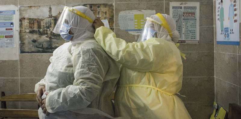 Un'infermiera aiuta un collega a indossare i dispositivi di protezione individuale in un ospedale di Giza
(Menna Hossam/dpa via ANSA)