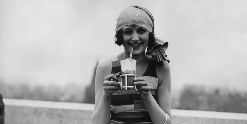 Una modella di costumi da bagno con una bevanda ghiacciata, nel 1928. (H. F. Davis/Topical Press Agency/Getty Images)