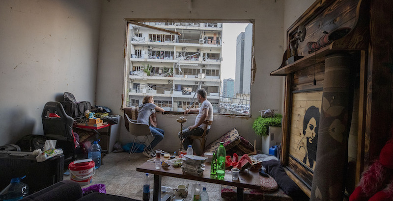 Una coppia si riposa guardando fuori dalla finestra divelta del proprio appartamento (AP Photo/Hassan Ammar)