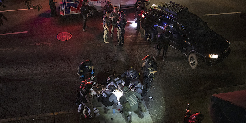 Agenti di polizia e addetti ai soccorsi attorno all'uomo colpito durante gli scontri a Portland del 29 agosto 2020 (La Presse/AP Photo / Paula Bronstein)