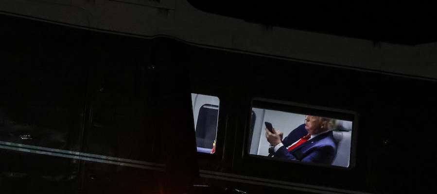 In una foto di agosto 2020, il presidente americano Donald Trump guarda il suo telefono a bordo dell'elicottero presidenziale Marine One (Samuel Corum/Getty Images)