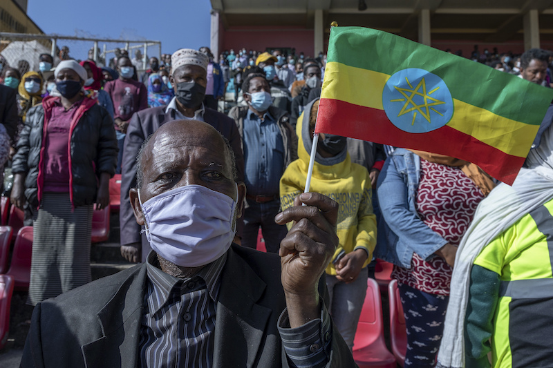 Un uomo sventola la bandiera nazionale etiope mentre aspetta di donare il sangue per sostenere l’operazione dell’esercito nel Tigrè 


(AP Photo/Mulugeta Ayene)