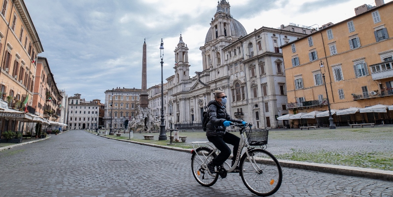 A woman rides a bicycle in Piazza Navona empty square in Rome, during the Coronavirus (Covid-19) emergency