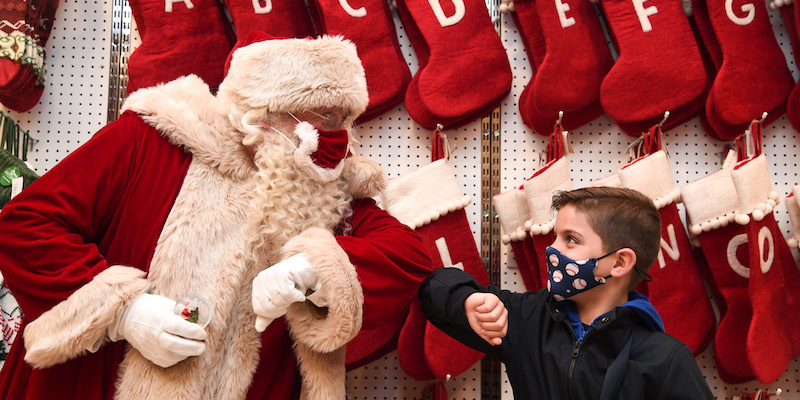 Un Babbo Natale saluta un bambino all'inaugurazione del settore delle decorazioni natalizie del centro commerciale Selfridges di Oxford Street, a Londra, il 12 ottobre 2020 (Eamonn M. McCormack/Getty Images)
