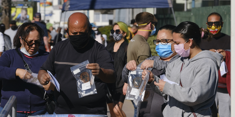 Persone lasciano il loro kit per il test sul coronavirus in un contenitore in un sito di raccolta, nel quartiere di North Hollywood a Los Angeles (Richard Vogel/AP Photo, LaPresse)