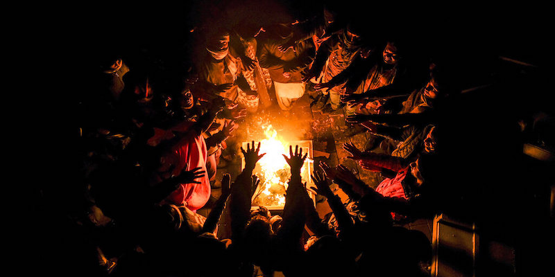 Migranti si scaldano le mani sul fuoco nel campo profughi distrutto di Lipa, in Bosnia (AP Photo/Kemal Softic, LaPresse)